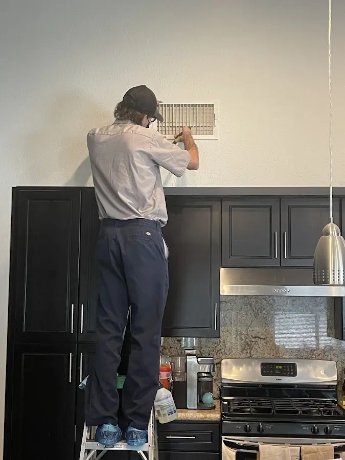 Technician inspecting an air vent during HVAC service in Woodlake